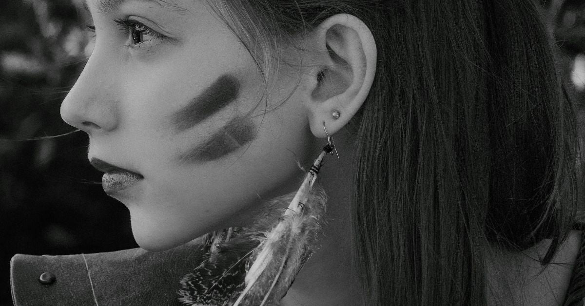 A Woman Wearing Feather Earrings and Marks on Cheeks